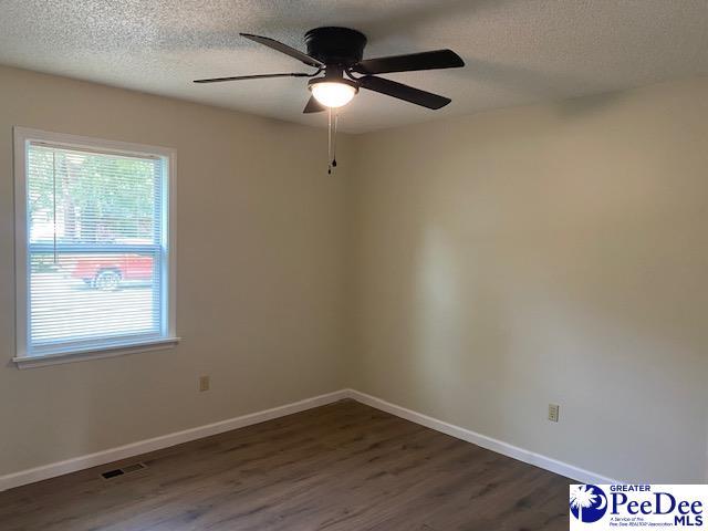 empty room featuring ceiling fan, dark hardwood / wood-style flooring, and a textured ceiling