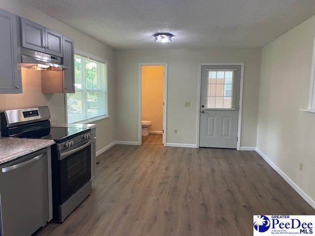 kitchen with stainless steel appliances, gray cabinets, hardwood / wood-style floors, and a textured ceiling