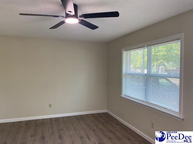 unfurnished room with ceiling fan, dark hardwood / wood-style flooring, and a textured ceiling