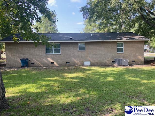 back of property featuring central AC unit and a lawn