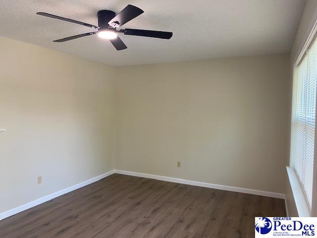 empty room with ceiling fan, dark hardwood / wood-style floors, and a textured ceiling