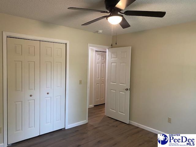 unfurnished bedroom featuring dark wood-type flooring, a closet, and a textured ceiling