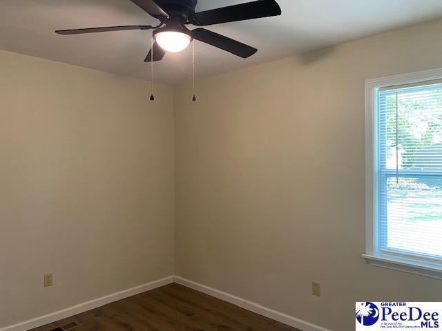 empty room with ceiling fan and dark hardwood / wood-style flooring