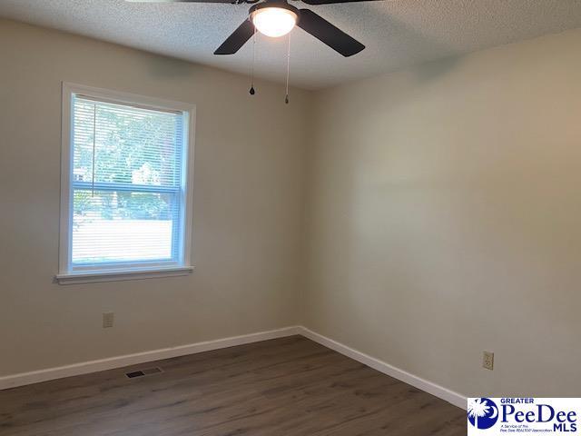 empty room featuring dark hardwood / wood-style flooring, ceiling fan, and a textured ceiling