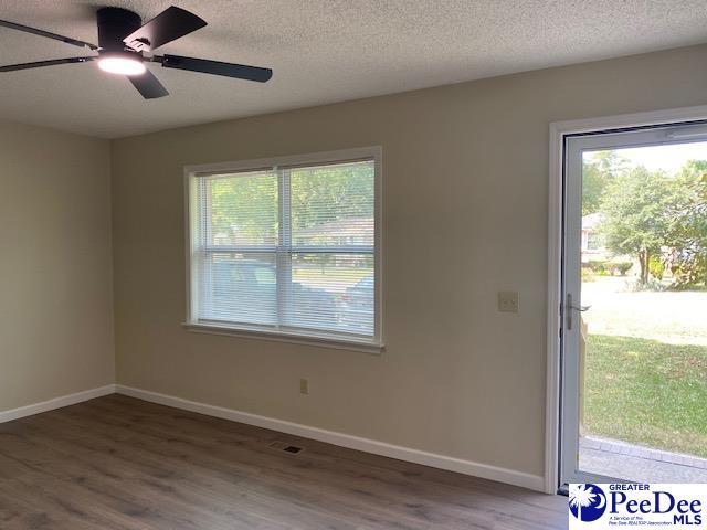 unfurnished room with ceiling fan, dark hardwood / wood-style flooring, and a textured ceiling