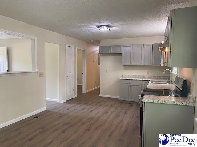 kitchen with dark hardwood / wood-style flooring, sink, stainless steel range, and a textured ceiling