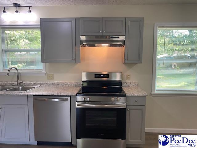 kitchen featuring hardwood / wood-style floors, sink, gray cabinetry, stainless steel appliances, and a textured ceiling