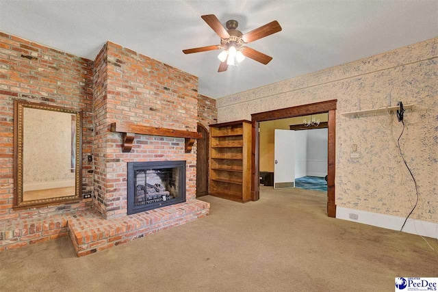 unfurnished living room with carpet floors, ceiling fan, a fireplace, and a textured ceiling