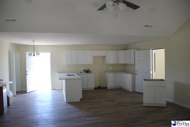 kitchen featuring ceiling fan with notable chandelier, white cabinetry, hanging light fixtures, a center island, and dark wood-type flooring