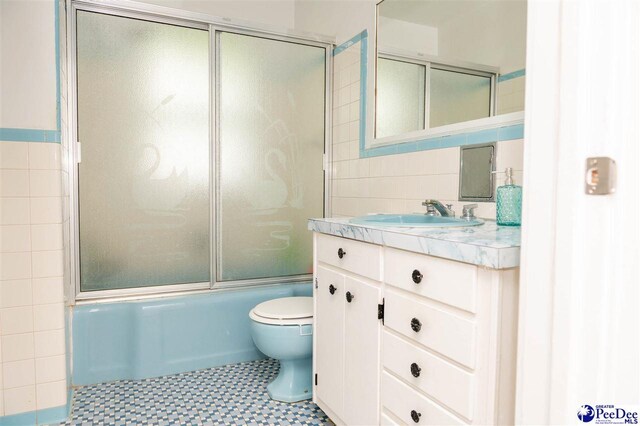 full bathroom featuring tile walls, vanity, shower / bath combination with glass door, and toilet