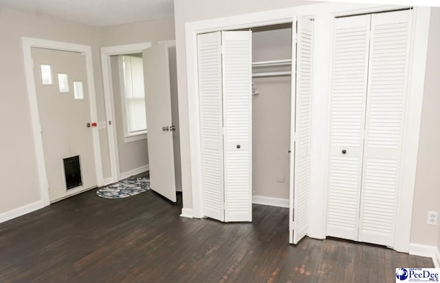 unfurnished bedroom featuring multiple closets and dark hardwood / wood-style flooring