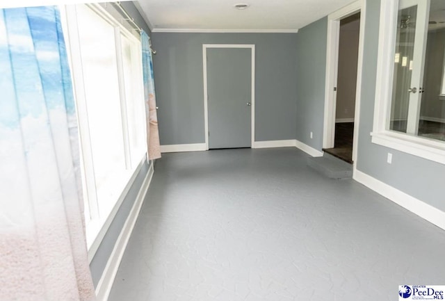 unfurnished room featuring concrete flooring, ornamental molding, and a wealth of natural light