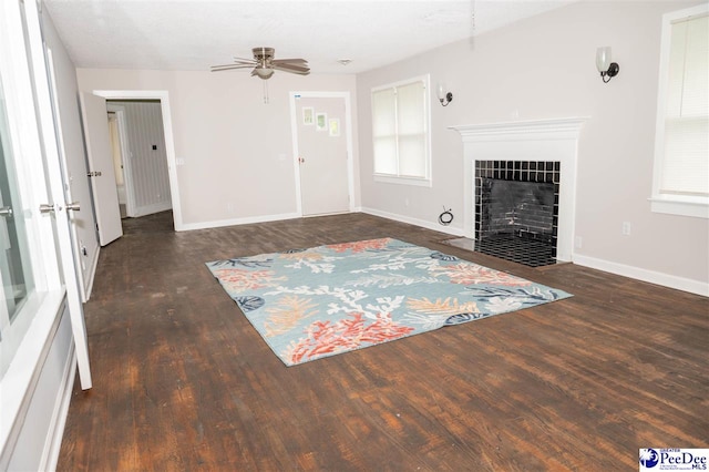 unfurnished living room featuring dark wood-type flooring, ceiling fan, and a fireplace