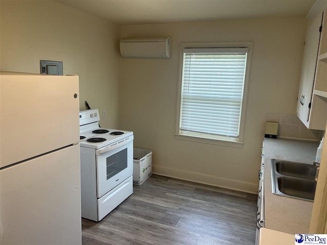 309 E Proctor St, Mullins, SC 29574 - kitchen with wood finished floors, white appliances, light countertops, an AC wall unit, and a sink