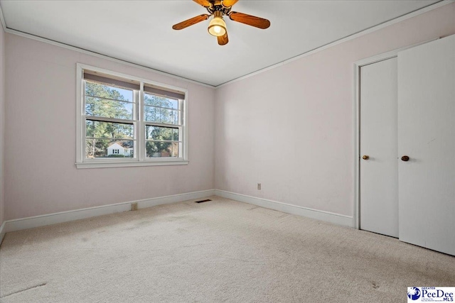 unfurnished bedroom featuring crown molding, light carpet, ceiling fan, and baseboards