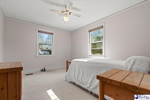 bedroom featuring baseboards, multiple windows, visible vents, and light colored carpet