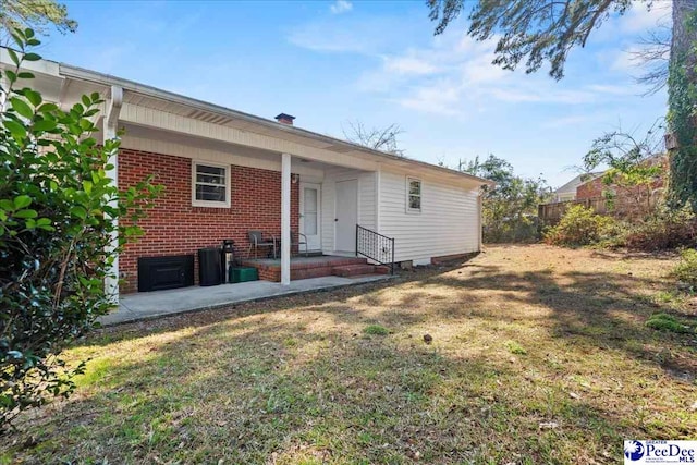 rear view of house featuring a yard and brick siding