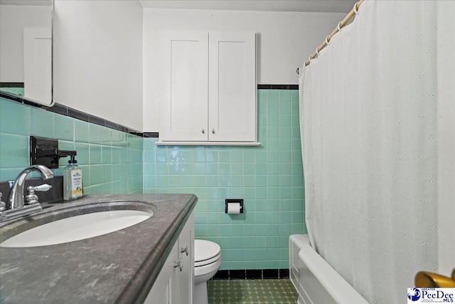 bathroom featuring toilet, tile walls, vanity, wainscoting, and tile patterned floors