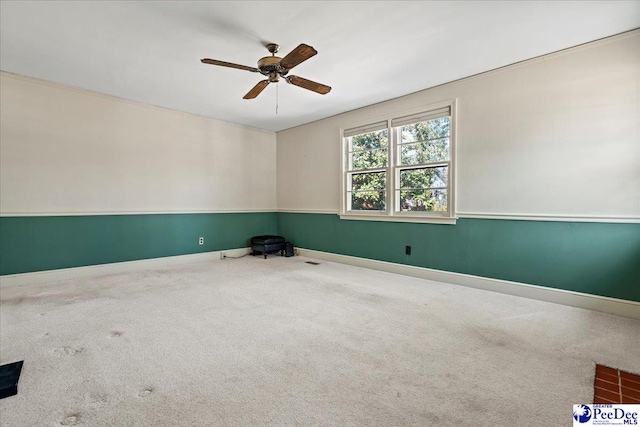 carpeted spare room featuring visible vents, ceiling fan, and baseboards