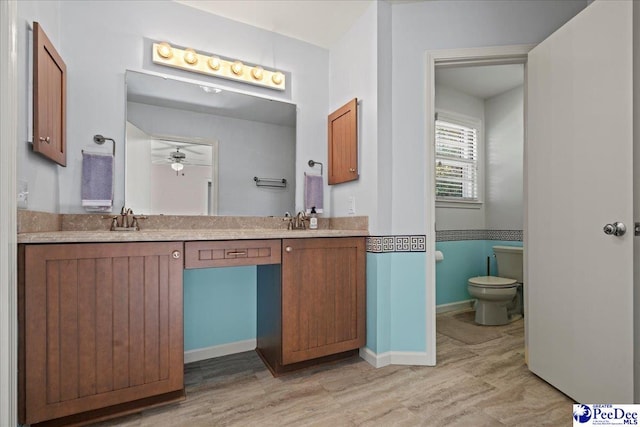 bathroom featuring double vanity, a sink, toilet, and baseboards