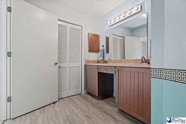 bathroom with a closet, wood finished floors, and vanity