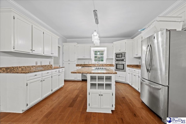 kitchen featuring appliances with stainless steel finishes, dark stone countertops, a center island, white cabinets, and decorative light fixtures