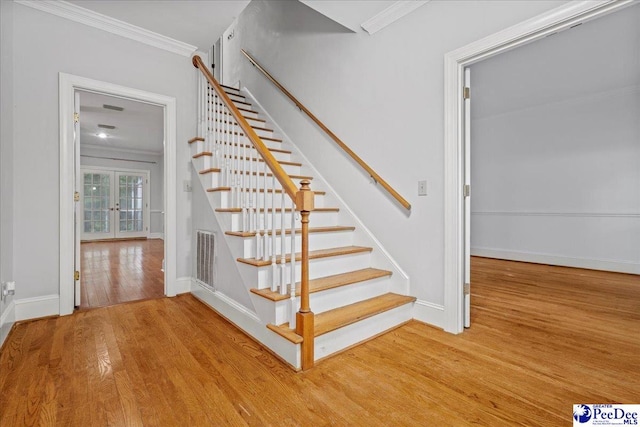 stairs featuring hardwood / wood-style flooring, crown molding, and french doors