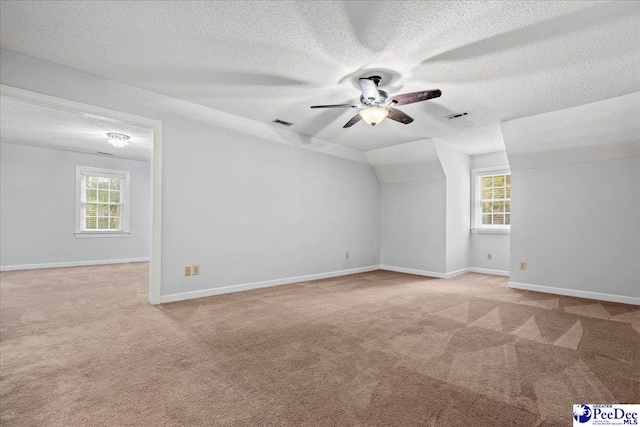 carpeted empty room with lofted ceiling, ceiling fan, and a textured ceiling