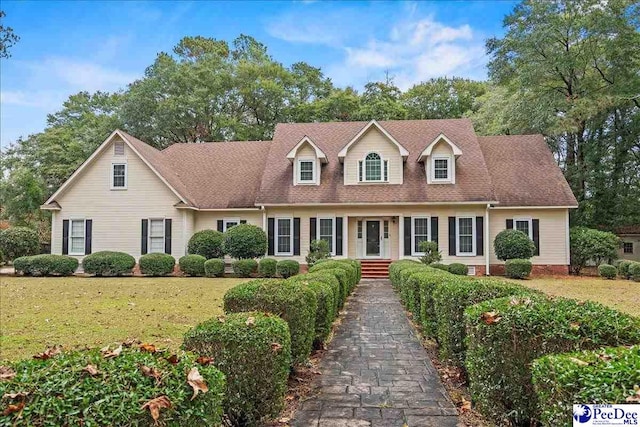 new england style home with a front lawn and a shingled roof