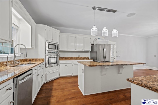 kitchen featuring appliances with stainless steel finishes, white cabinetry, sink, dark hardwood / wood-style flooring, and a center island