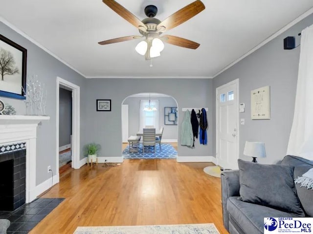 1417 Woods Rd, Florence, SC 29501 - living room with arched walkways, a ceiling fan, light wood-style flooring, a tiled fireplace, and ornamental molding