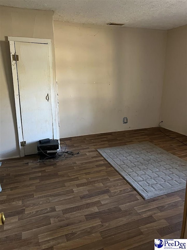 unfurnished room featuring dark hardwood / wood-style flooring and a textured ceiling