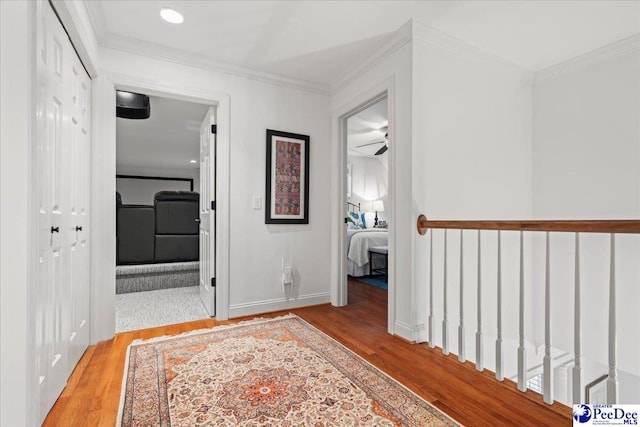 hallway with crown molding, baseboards, and wood finished floors