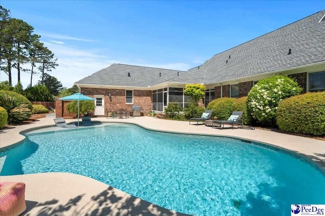 view of swimming pool featuring a sunroom, fence, a fenced in pool, and a patio area