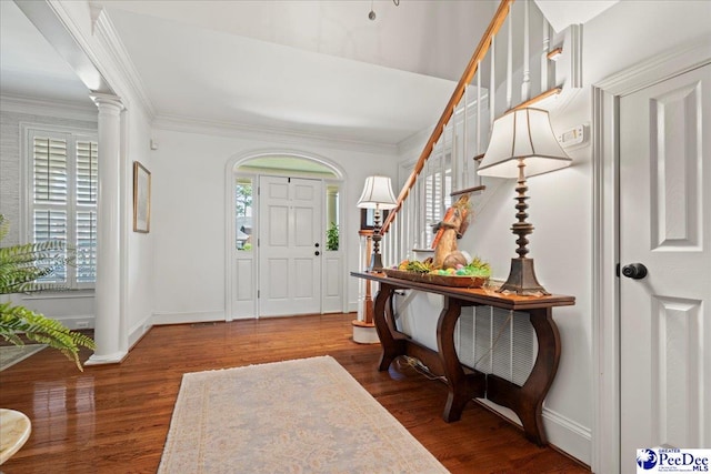 foyer with crown molding, wood finished floors, and stairway