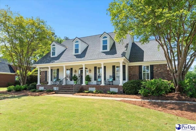cape cod-style house featuring a porch, brick siding, a shingled roof, and a front lawn