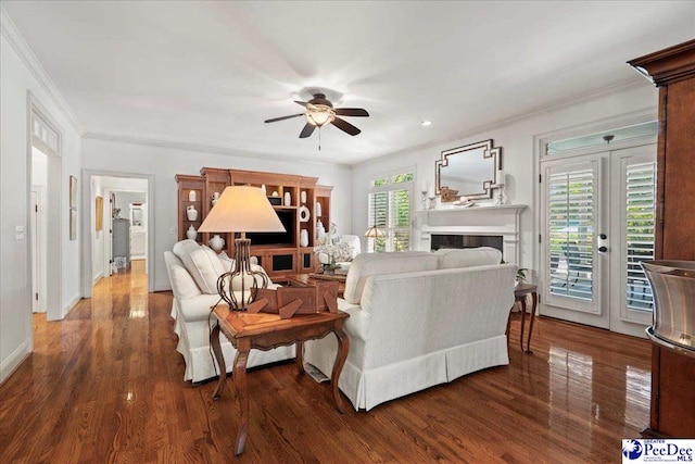 living area featuring crown molding, a ceiling fan, and dark wood finished floors