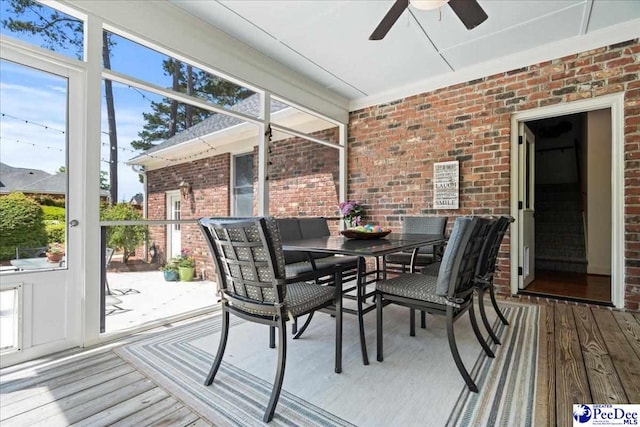 sunroom / solarium with outdoor dining area and a ceiling fan