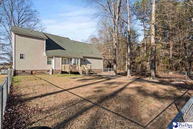 rear view of house with a wooden deck and a lawn