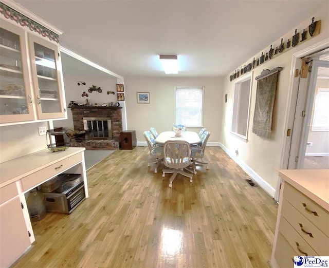 dining room featuring light wood-type flooring and a fireplace