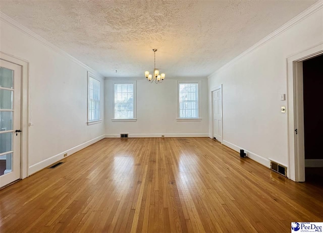 empty room with wood-type flooring, a textured ceiling, a notable chandelier, and crown molding