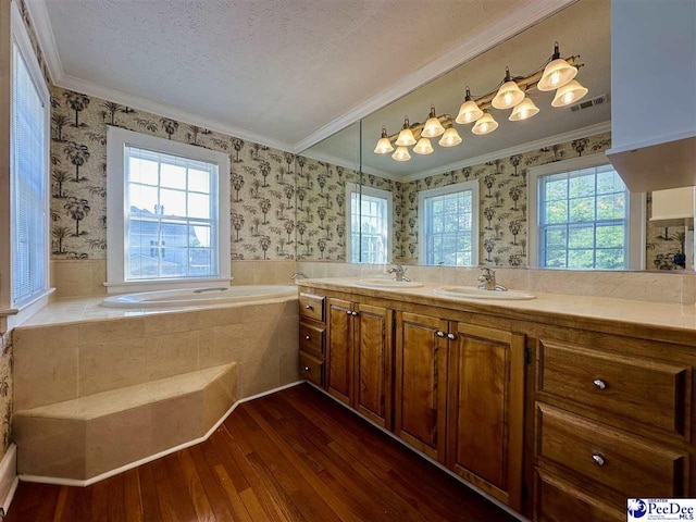 bathroom with ornamental molding, tiled tub, hardwood / wood-style floors, and plenty of natural light