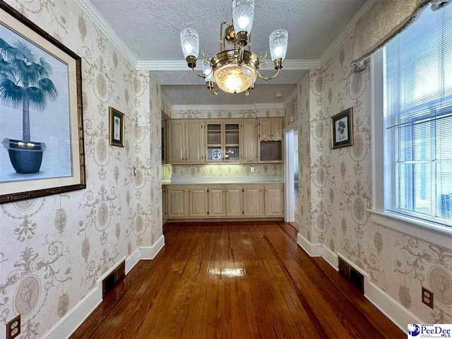 corridor with ornamental molding, dark hardwood / wood-style floors, a textured ceiling, and a chandelier