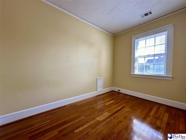 empty room with ornamental molding, wood-type flooring, and a textured ceiling