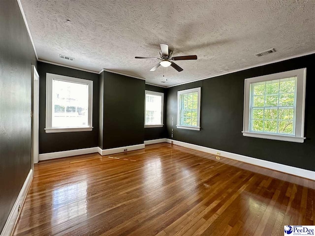 spare room with crown molding, a healthy amount of sunlight, and hardwood / wood-style floors