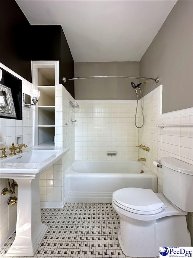 bathroom with tiled shower / bath, toilet, and tile walls