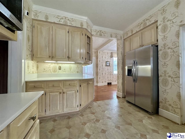 kitchen with stainless steel appliances, ornamental molding, light brown cabinetry, and a textured ceiling