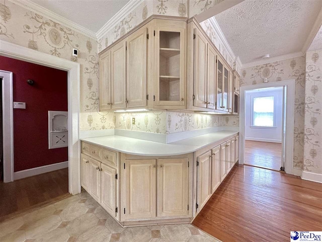 kitchen with ornamental molding, a textured ceiling, and light hardwood / wood-style flooring