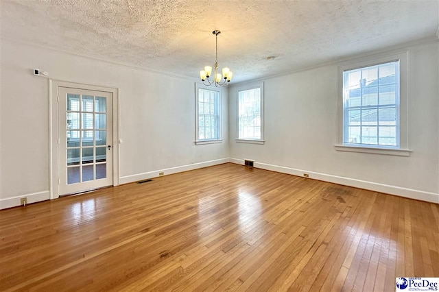 unfurnished room with hardwood / wood-style floors, a textured ceiling, and a chandelier