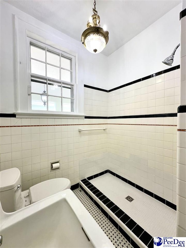 bathroom with tile walls, toilet, and tiled shower